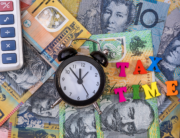 A small clock and block letters saying 'Tax Time' placed on Australian money.