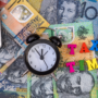 A small clock and block letters saying 'Tax Time' placed on Australian money.